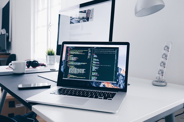 laptopwithcode_webupdates Laptop on a white desk with code on the screen