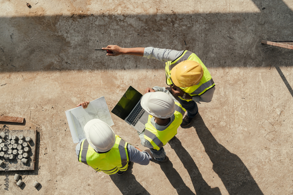 AdobeStock_595922327_Preview Project team reviewing plans on a laptop at a construction site
