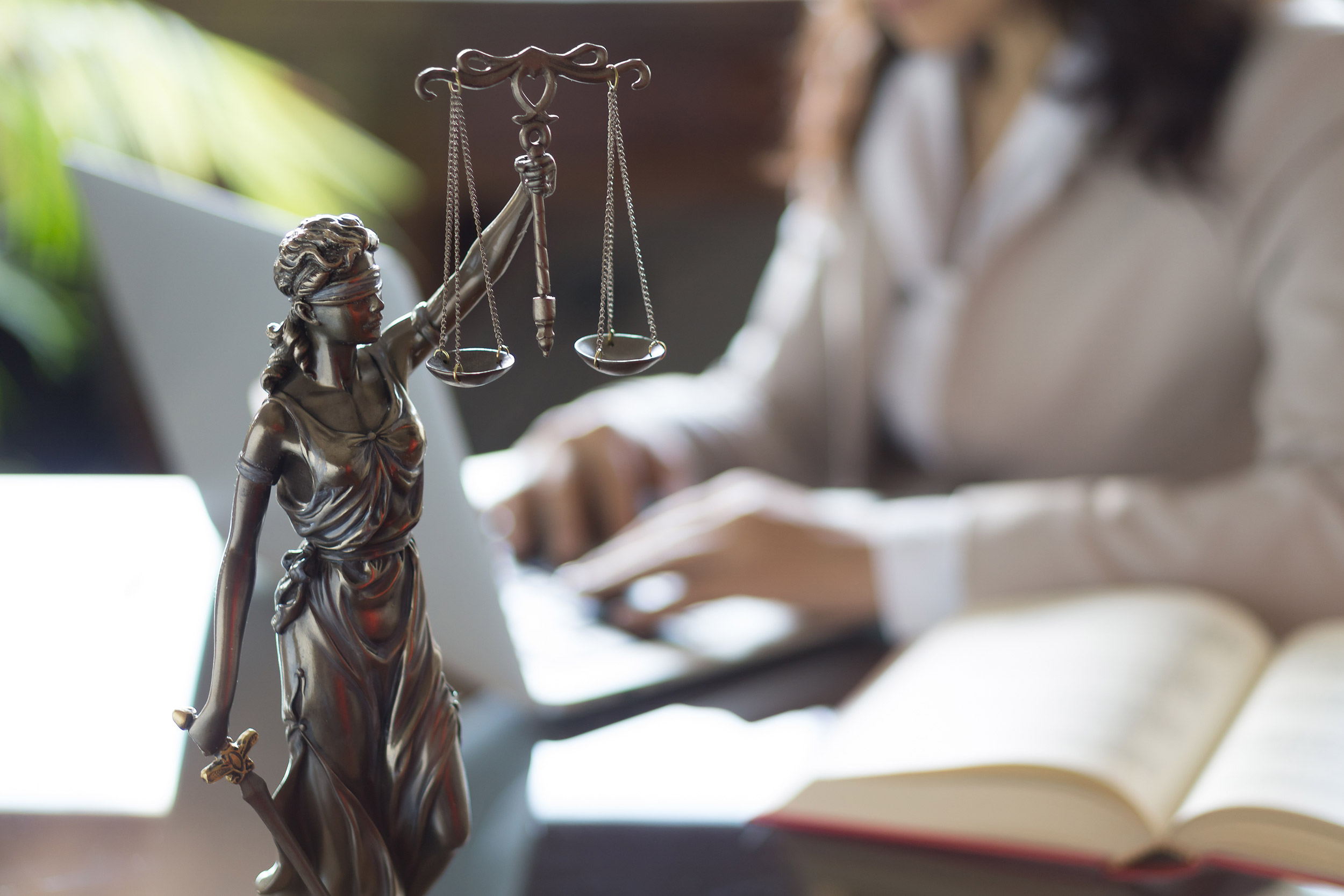 Statue of Justice and a lawyer working on a laptop